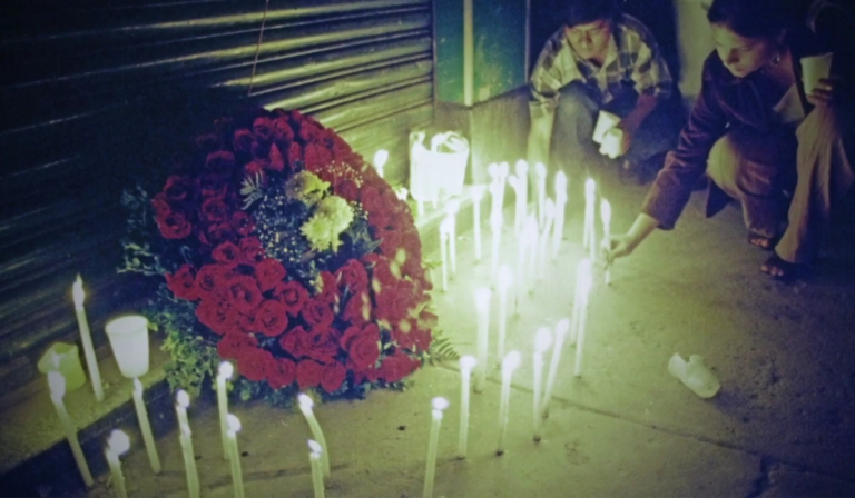 Imagen de primera manifestación LGBT en Guatemala en memoria de Conchita Alonso. Se ve una activista con una vela prendida y de fondo más velas prendidas y un altar de flores.
